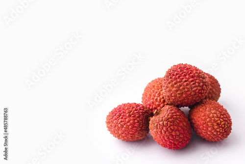 unpeeled lychee fruits on a white background, copy space