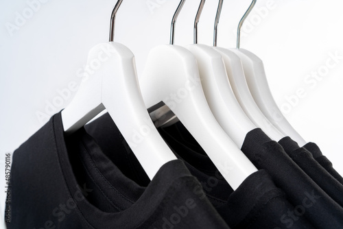 Fototapeta Black T-shirt on hangers on metal rack isolated on white background