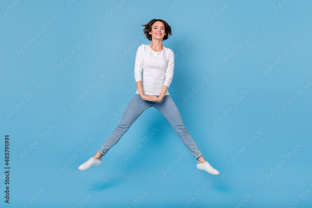Full size photo of crazy cheerful lady jumping fooling around travel on weekend isolated on blue color background Full size photo of crazy cheerful lady jumping fooling around travel on weekend isolated on blue color background