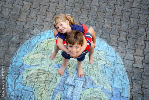 Little preschool girl and school kid boy with earth globe painting with colorful chalks on ground. Happy earth day concept. Creation of children for saving world, environment and ecology. © Irina Schmidt
