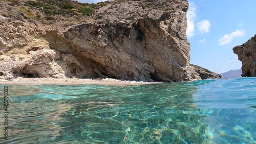 Underwater split video of beautiful paradise pebble rocky bay of Kaladi with turquoise crystal clear sea and small caves, Kythira island, Ionian, Greece photo