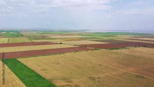 Wind turbines among the agricultural fields on the seashore. Aerial view. Green energy concept photo