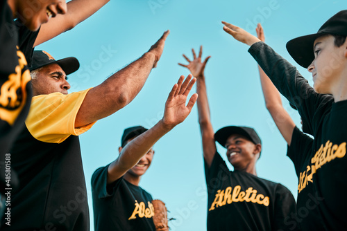 We play as one, we win as one. Shot of a team of young baseball players joining their hands together in a huddle during a game.