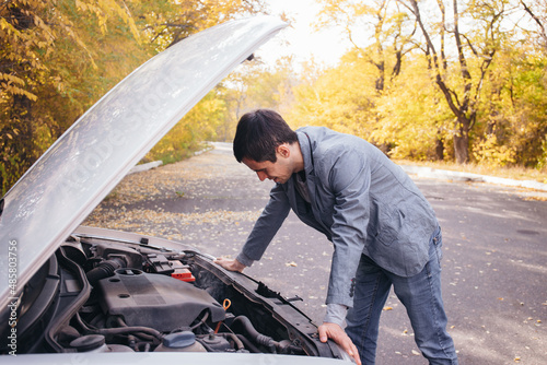 A man looks under the quota of a broken car. © artem_goncharov