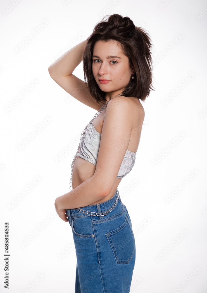A beautiful woman posing in a jewelry bra with chains and blue jeans isolated on white background. Mockup for party or dance concept with space for text A beautiful woman posing in a jewelry bra with chains and blue jeans isolated on white background. Mockup for party or dance concept with space for text
