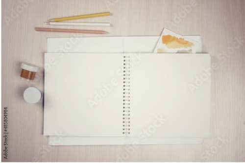 Blank notebook on rings with pencils and paints, artist's desktop, mockup