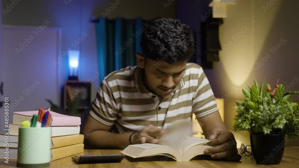 Young college student not able to understanding from book while reading or studying night before the examination - concept of confusion, laziness, negligence and struggling to study
