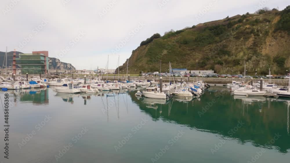 4k video of ships and boats docked at the Laredo Marina reflecting the berths and walkways in the water and the La Marina building in the background