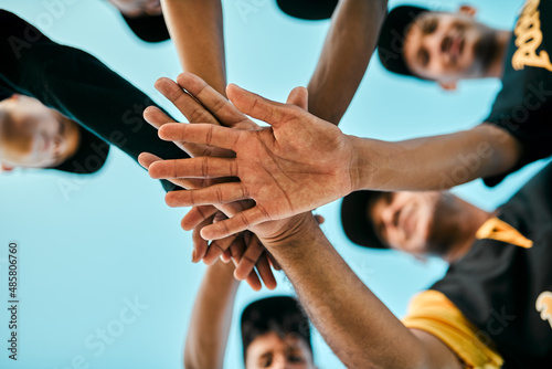 Every player plays a large role. Shot of a team of young baseball players joining their hands together in a huddle during a game.