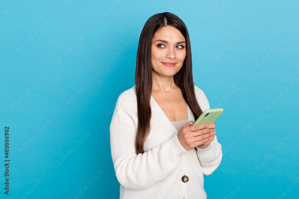 Photo of dreamy woman wear white cardigan writing modern device looking empty space isolated blue color background Photo of dreamy woman wear white cardigan writing modern device looking empty space isolated blue color background