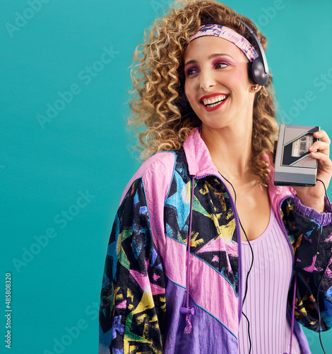 Nothing makes me feel as good as 80s music. Studio shot of a young woman holding a cassette player while dressed in 80s clothing.