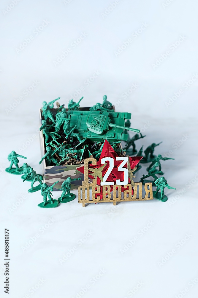 February 23 holiday greeting russian text, plastic toys soldiers and gift box on abstract marble background close up. Defender of Fatherland Day holiday  concept