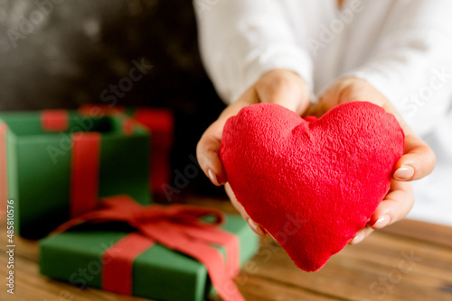 The woman took out a toy heart from a gift box and holds it in her hands. Shallow depth of field. Space for text.