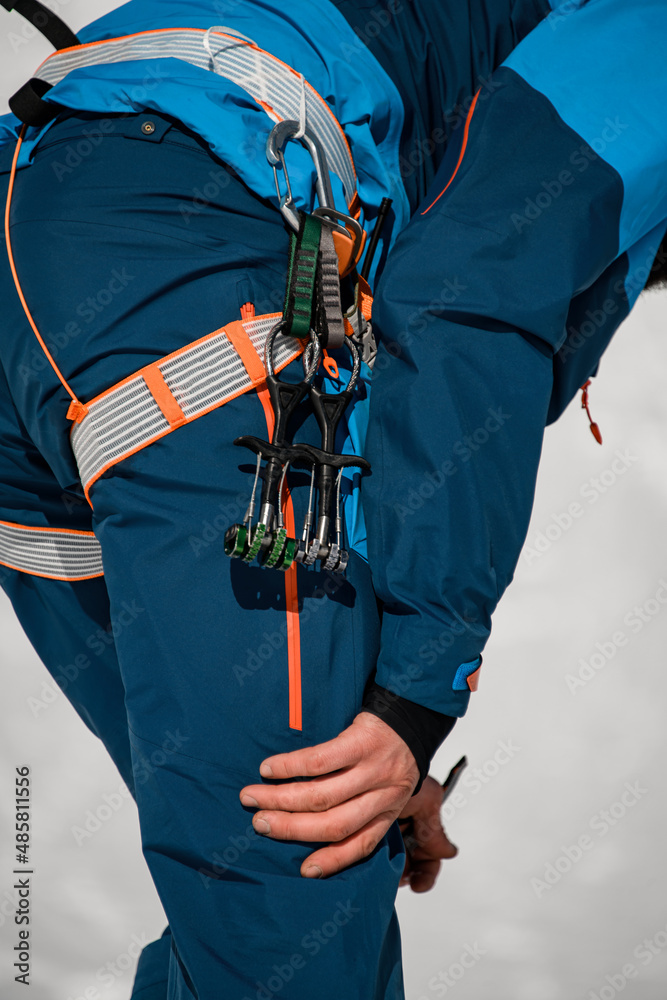 Close-up of the body part of a man in ski suit with climbing harness wearing on. Close-up of the body part of a man in ski suit with climbing harness wearing on.