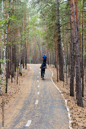 cyclists riding on a bike path in the forest