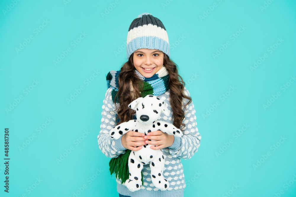happy smiling child in knitwear hold toy. teen girl on blue background. happy childhood.