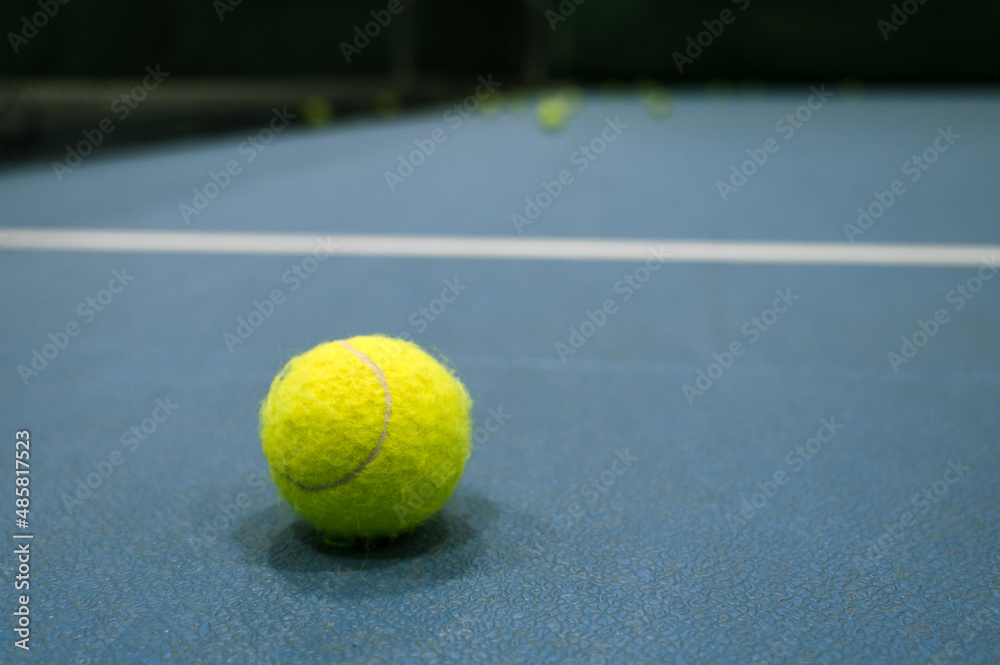 Close-up of tennis ball on blue hard tennis court.