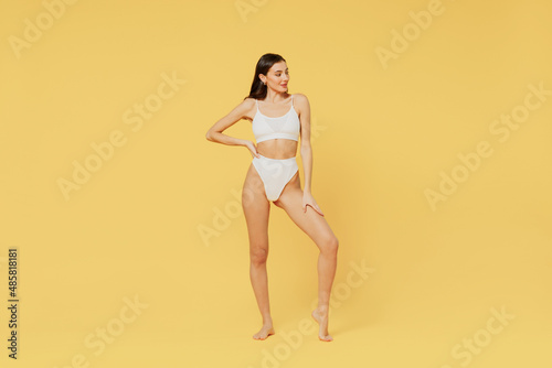 Full body young sexy brunette woman 20s wearing white underwear with perfect fit figure look aside on workspace isolated on plain yellow color background studio portrait. People female beauty concept
