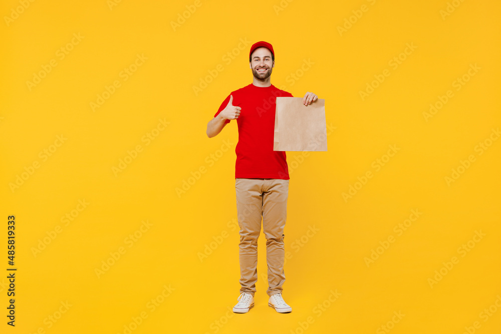 Full size delivery guy employee man in red cap T-shirt uniform workwear work as dealer courier hold brown clear blank craft paper takeaway bag mock up show thumb up isolated on plain yellow background Full size delivery guy employee man in red cap T-shirt uniform workwear work as dealer courier hold brown clear blank craft paper takeaway bag mock up show thumb up isolated on plain yellow background