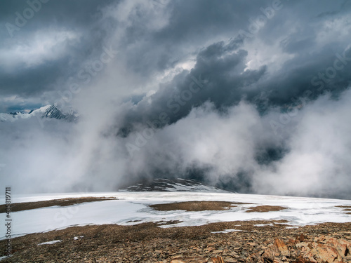 Awesome storm, a snowy atmospheric front in the mountains.Atmospheric alpine view to snow mountain range with low clouds. Scenic landscape with beautiful snow mountains in low clouds.