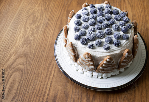 round blueberry cake with berries and marshmallows on a wooden background
