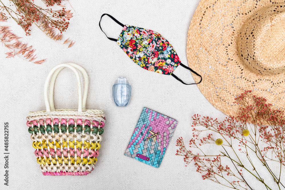 Obraz premium Flat lay of Coronavirus face mask covering with essential summer holiday travel items for a vacation in the Covid-19 pandemic