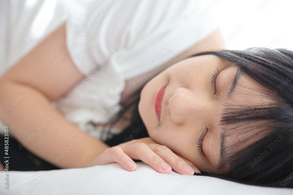 Beautiful young Asian woman sleeping on bed relaxing in the morning light with white room Beautiful young Asian woman sleeping on bed relaxing in the morning light with white room