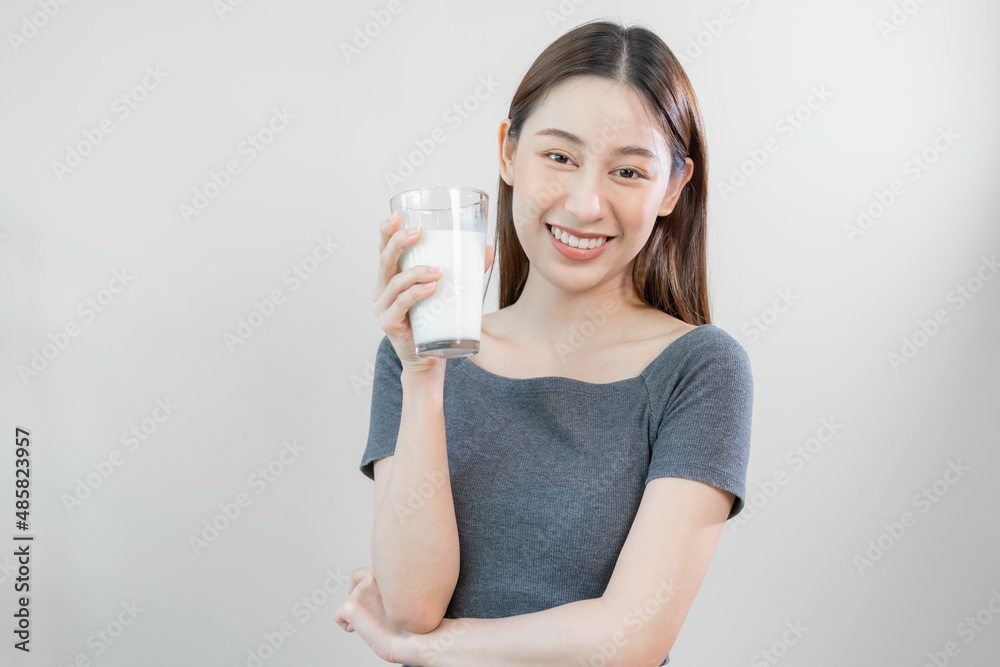 Happy, asian young woman, girl drinking a glass of white fresh, warm or hot dairy milk for calcium, vitamin wholesome good nutrition in morning. lifestyle, product healthy people, Isolated background. Happy, asian young woman, girl drinking a glass of white fresh, warm or hot dairy milk for calcium, vitamin wholesome good nutrition in morning. lifestyle, product healthy people, Isolated background.