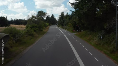 Wallpaper Mural Low flight above road, passing by cyclist riding on cyclist path. Ascending and revealing wooded flat landscape. Denmark Torontodigital.ca