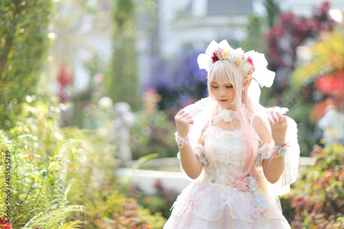 Beautiful young woman with white lolita dress with flowers garden Japanese fashion