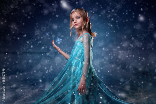 Young girl snow princess. Mystery fantasy girl in blue lush dress. Art background winter frozen and snow. photo