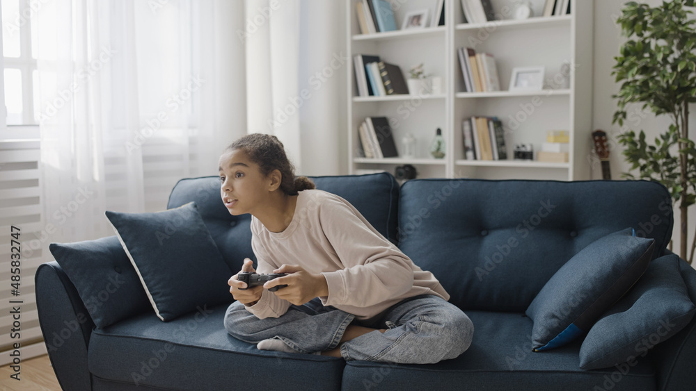 Teen girl playing video game at home, holding joystick, teenage leisure, fun