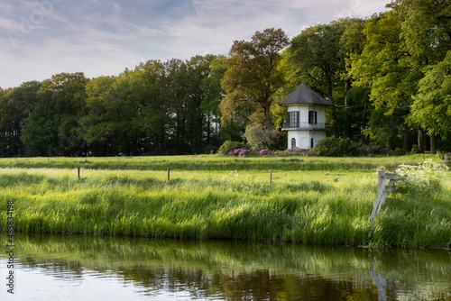 A small white tower in the middle of a meadow along a ditch in the Netherlands photo