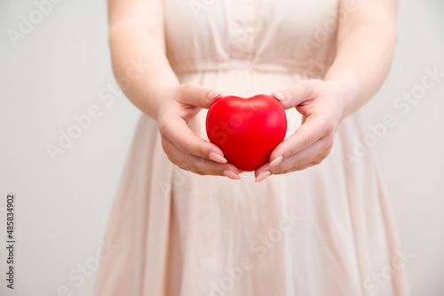 Pregnant woman with a belly tummy holding heart.Motherhood and pregnancy concept