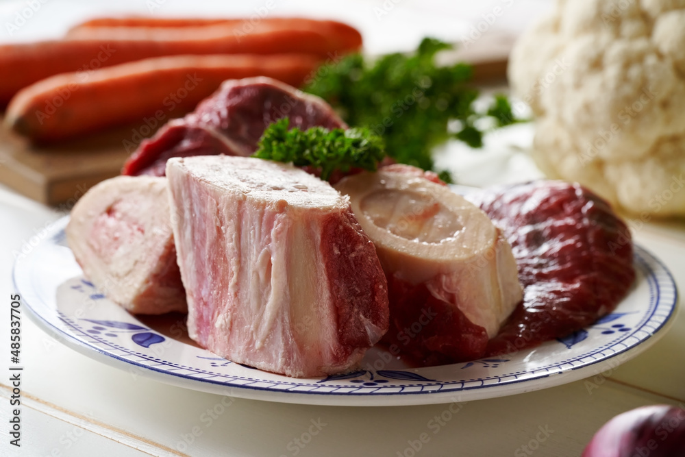 Ingredients for preparation of beef bone broth or soup - marrow bones, parsley, carrots, cauliflower
