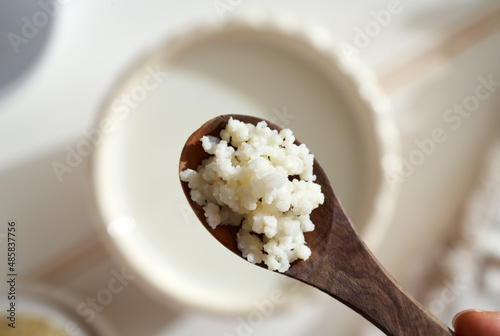 Milk kefir grains above a bowl of milk, top view