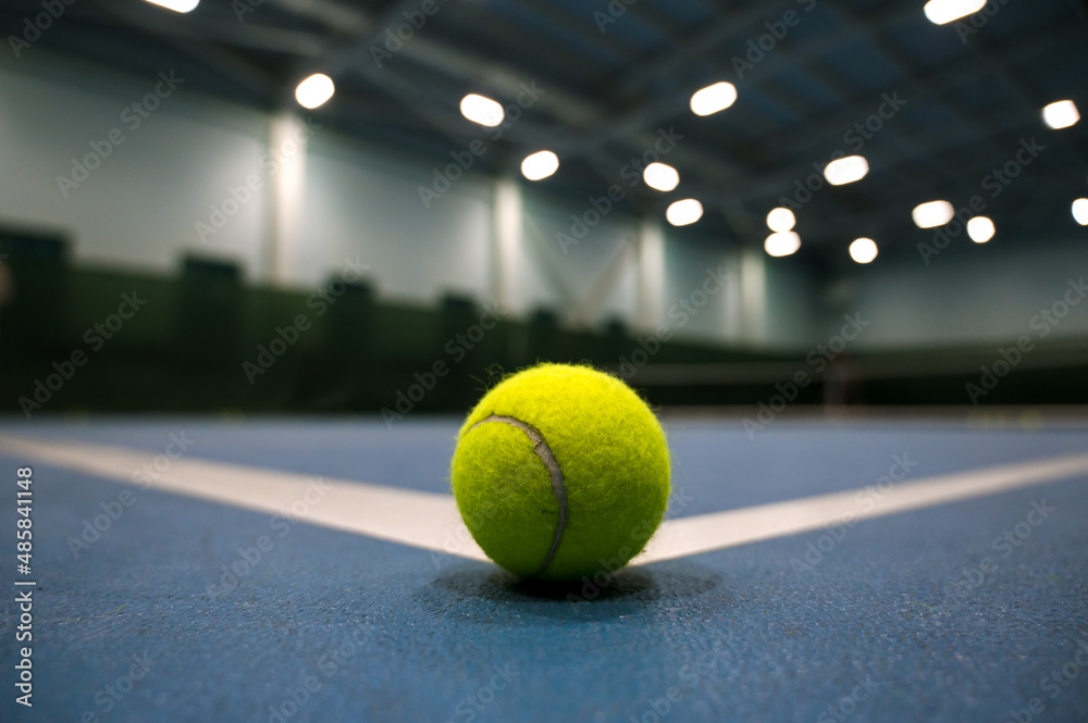 Close-up of tennis ball on blue hard court. Blurred background.