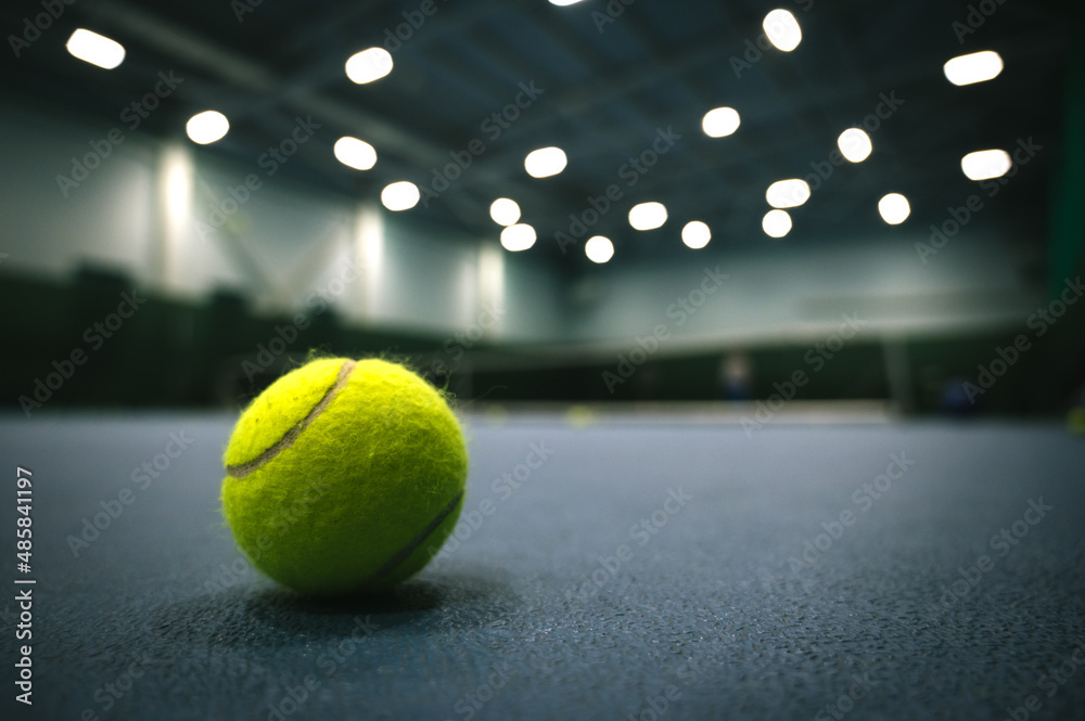 Close-up of tennis ball on blue hard court. Blurred background.