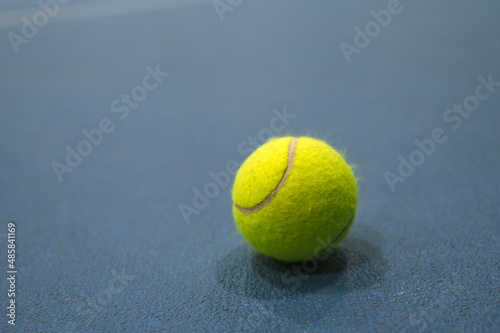 Close-up of tennis ball on blue hard court.