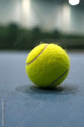 Close-up of tennis ball on blue hard court. Blurred background.