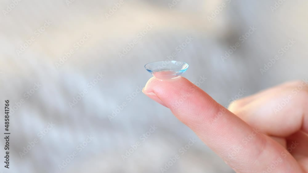 Women's finger with contact lens on a blurred background Women's finger with contact lens on a blurred background