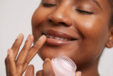 Close-up of smiling woman applying lip balm