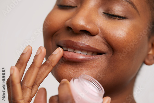 Close-up of smiling woman applying lip balm photo