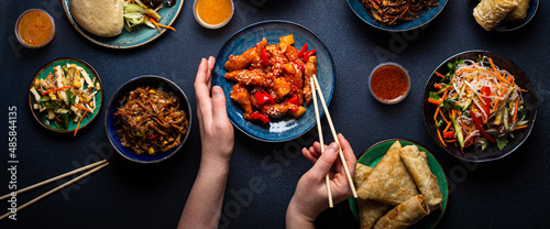 Fotografie Set of Chinese dishes on table, female hands holding chopsticks: sweet and sour