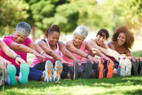 Having a laugh while limbering up. Shot of a group of people warming up outdoors. photo