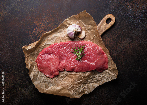 фотографія Beef lean raw fillet steak on baking paper with rosemary, garlic and spices on d