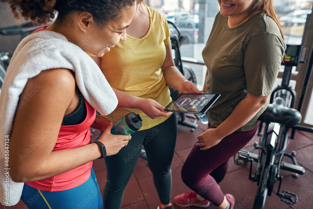 Partial of girls using sport app on digital tablet