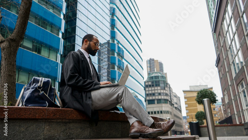 Business man using laptop outside office building