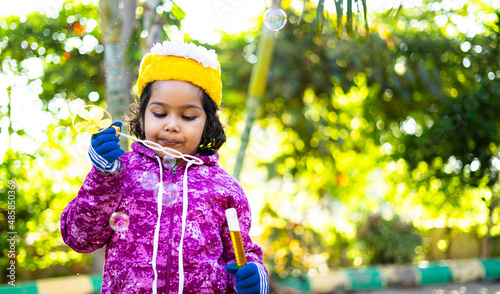 Close up shot of smilng girl kid having fun playing bubble game during winter at park - concept of Happiness, childhood liftstyles and playful activities. photo