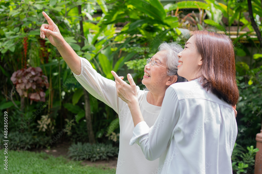 Obraz premium An old elderly Asian woman and walking in the backyard with her daughter. Concept of happy retirement With care from a caregiver and Savings and senior health insurance, Happy family